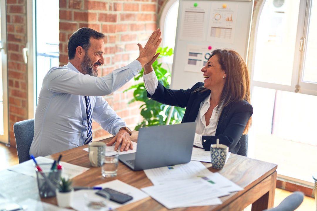 A man and a woman are giving each other a high five in an office.