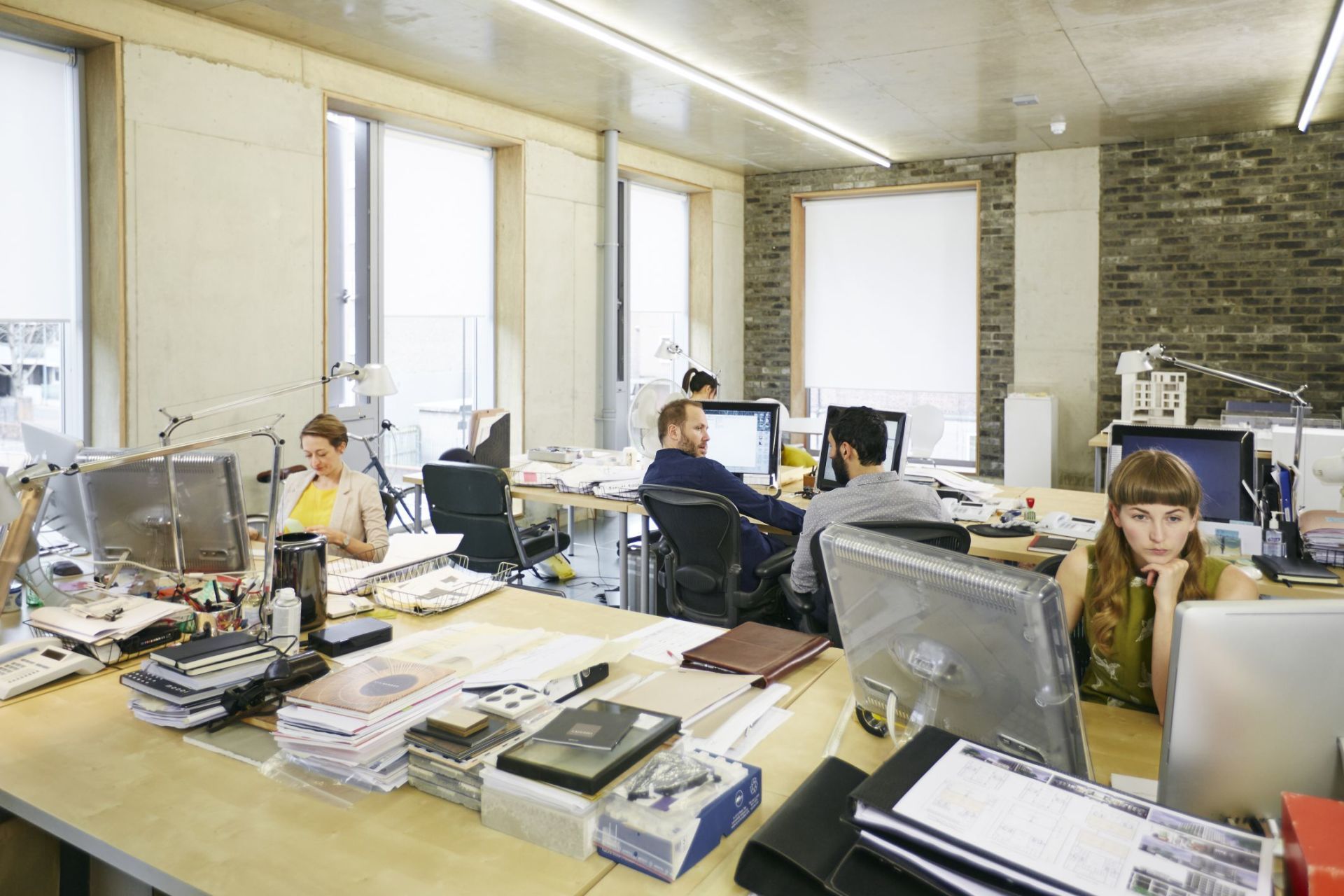 A group of people are sitting at desks in an office.