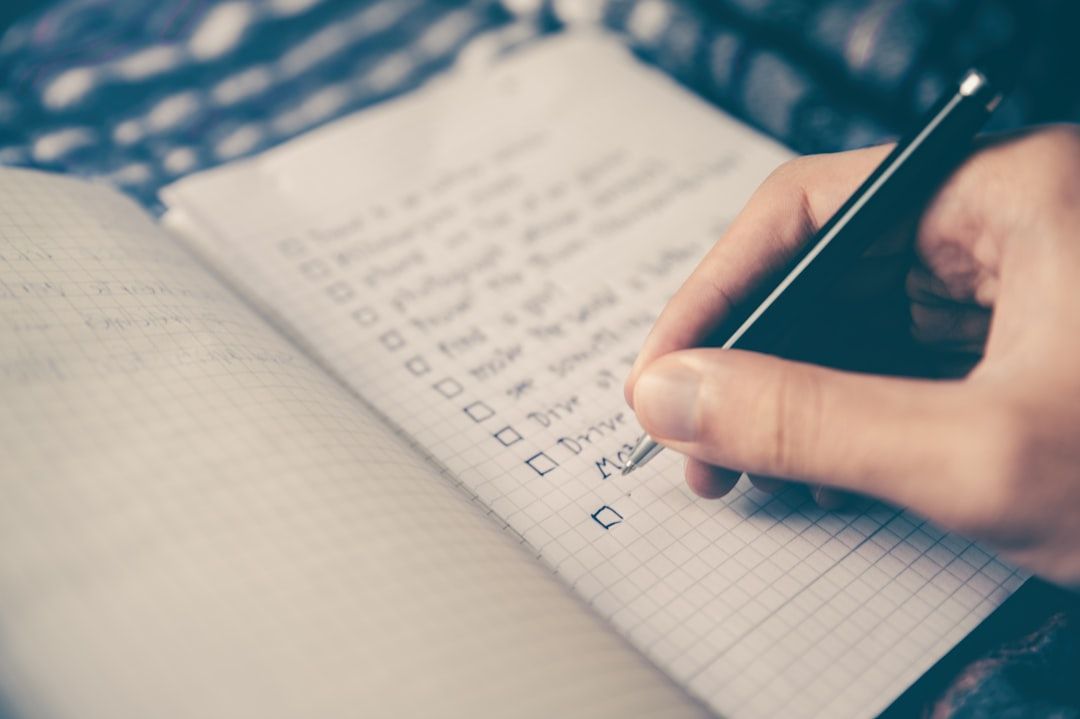 A person is writing on a checklist in a notebook.
