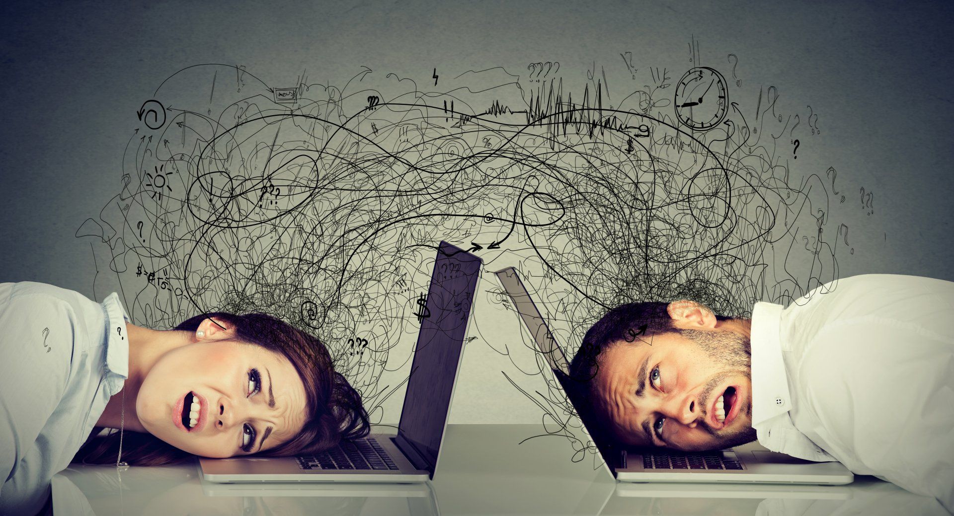 A man and a woman are laying on their backs in front of laptops.