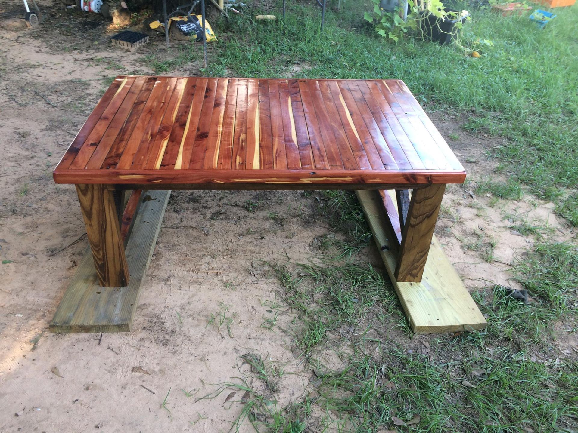 Wooden table with a shiny finish on a grassy outdoor area.