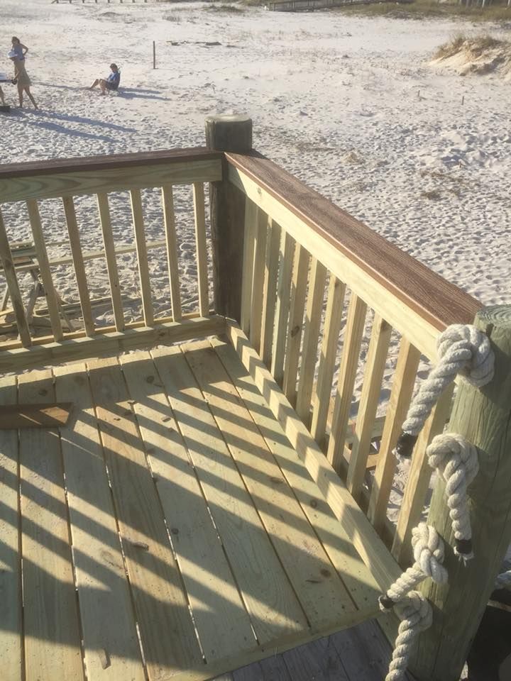 Wooden deck with rope accents, overlooking a sandy beach.