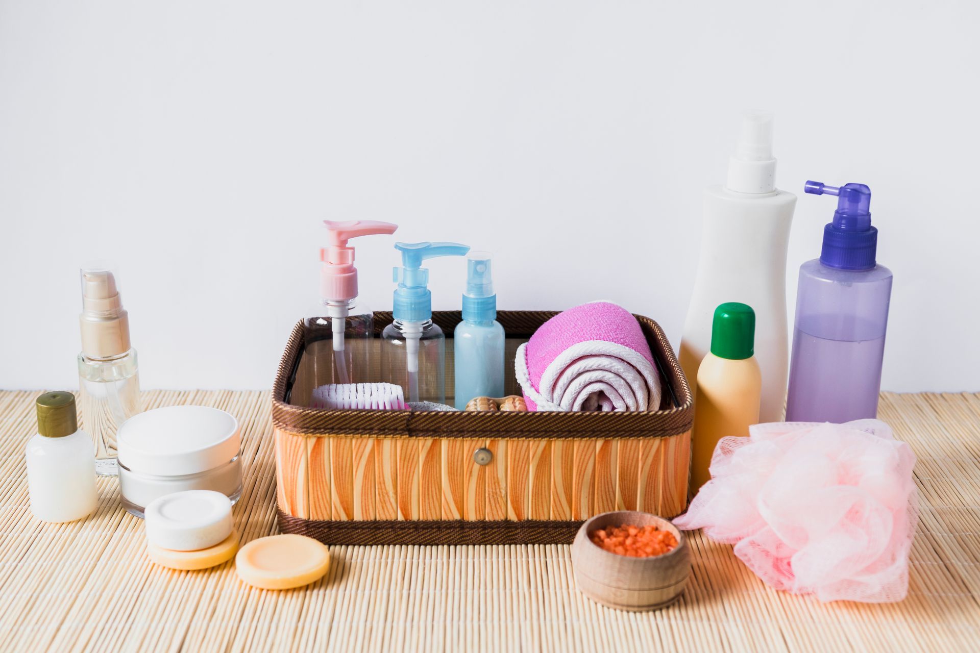 Cesta com kits de cosméticos variados, incluindo frascos, cremes, sabonetes e acessórios de beleza