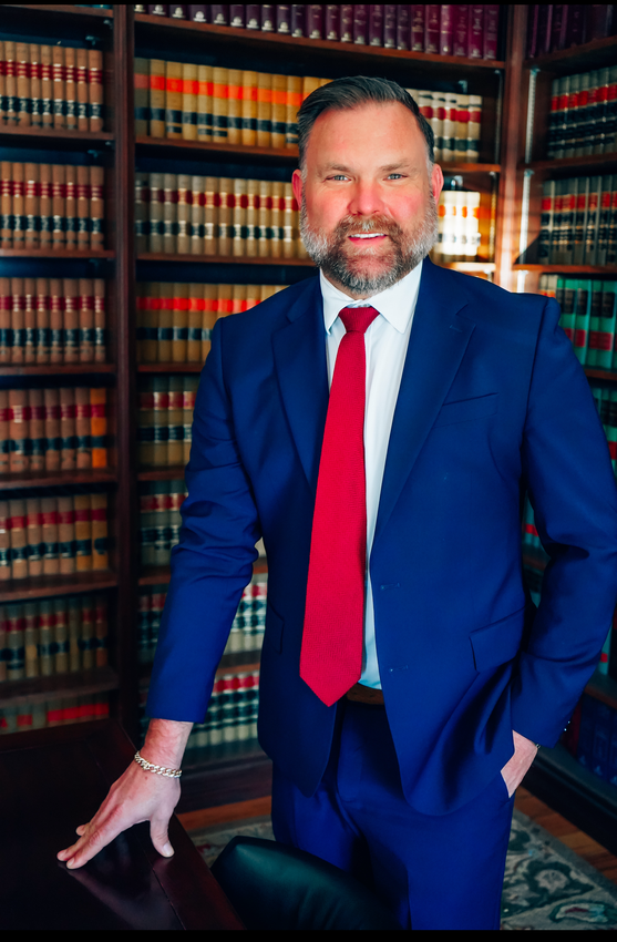 Man in a navy suit and red tie standing in front of law bookshelves