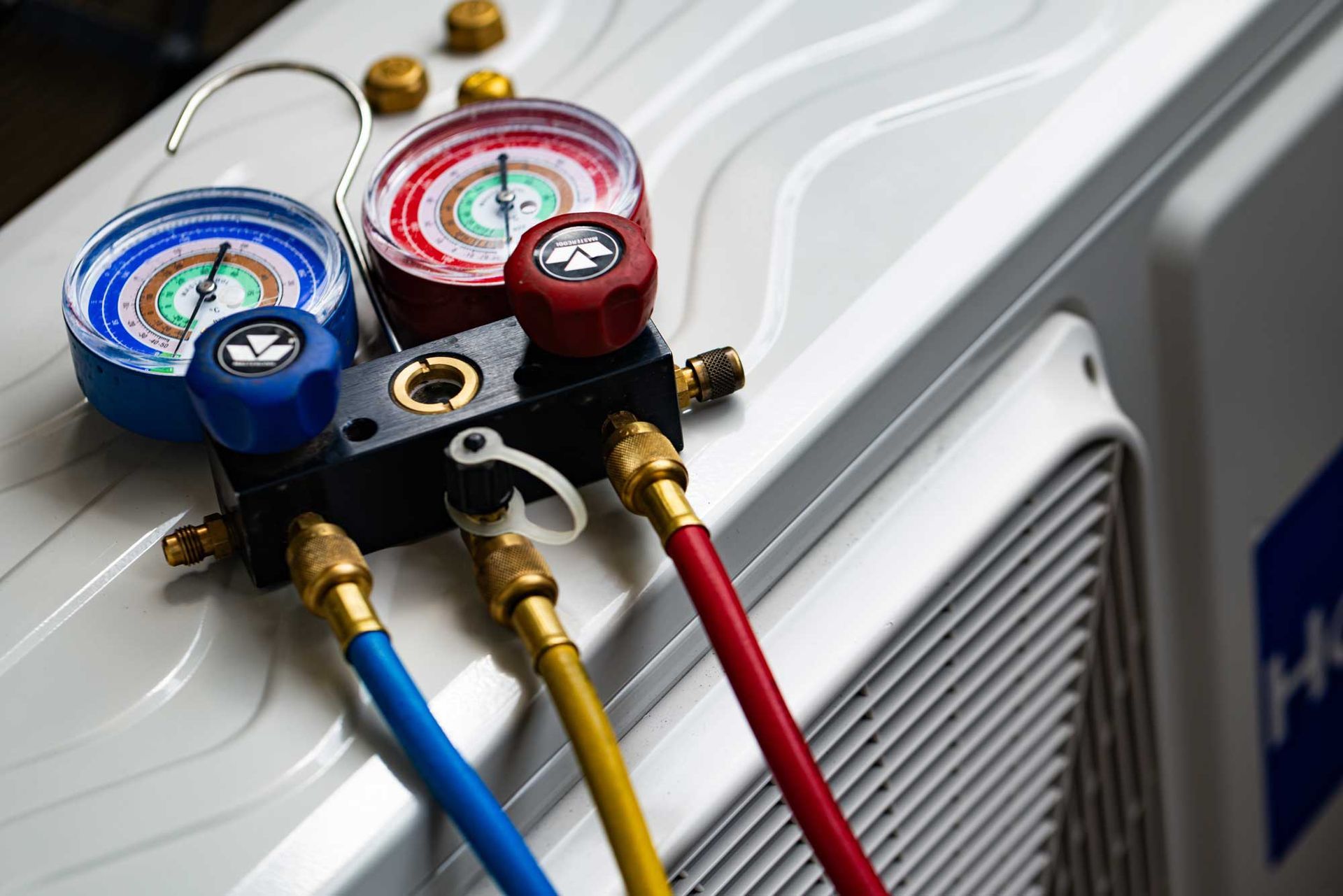 Emergency ac repair service showing HVAC pressure gauges connected to outdoor air conditioning unit.