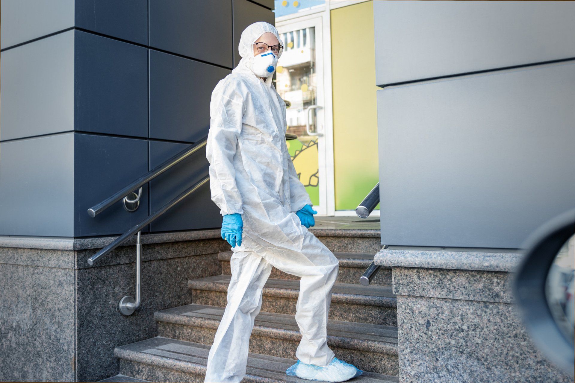 A man in a protective suit and mask is walking down stairs.