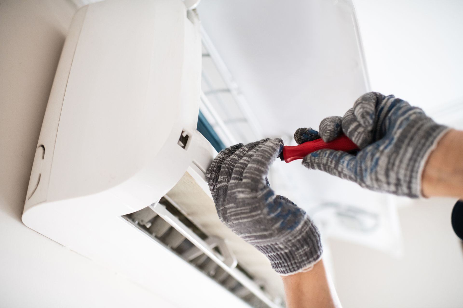 Close-up picture of a technician repairing an air conditioner at a residential property. 