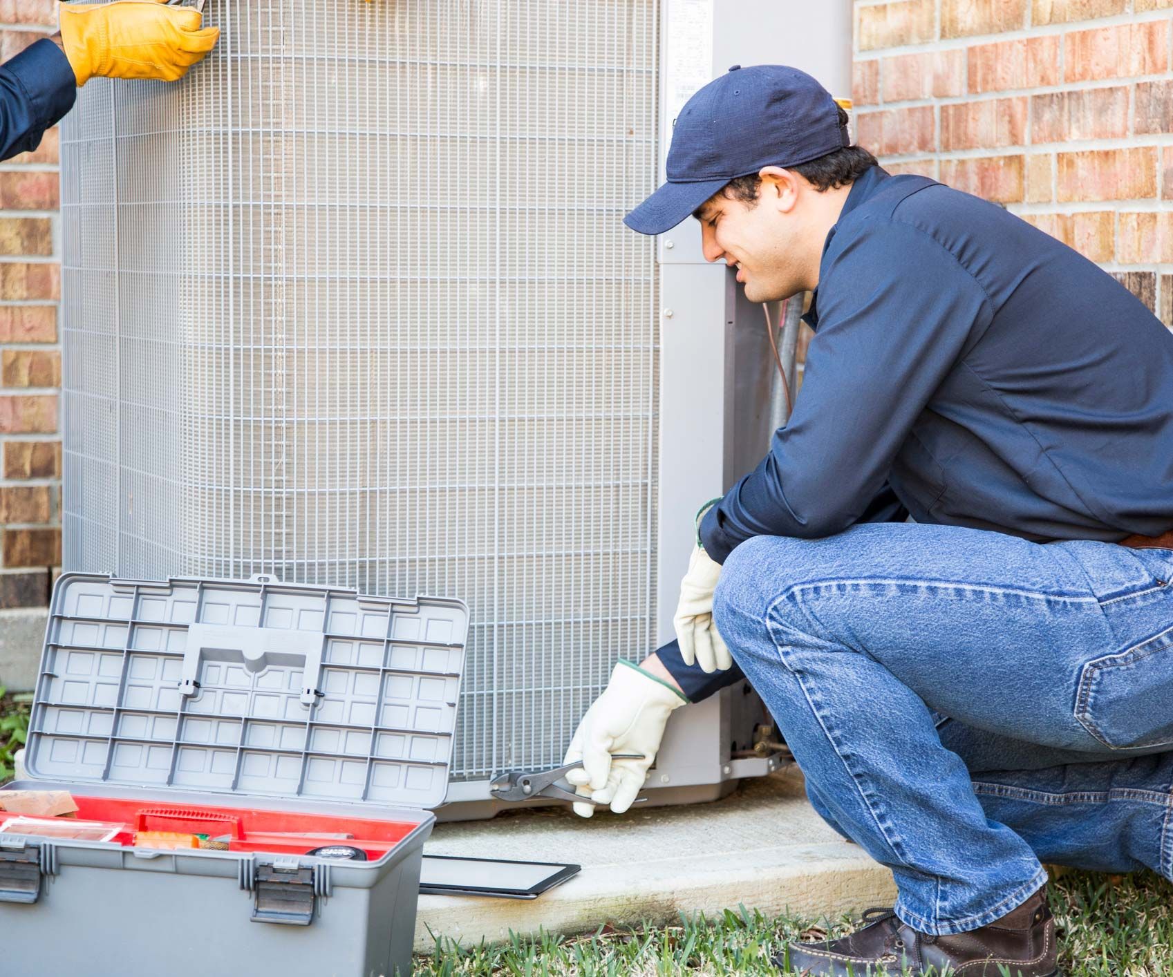 An experienced air conditioning contractor servicing an outdoor AC unit.
