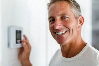 Commercial Heater Units — Guy Smiling While Holding The Thermostat In Cleveland, TN