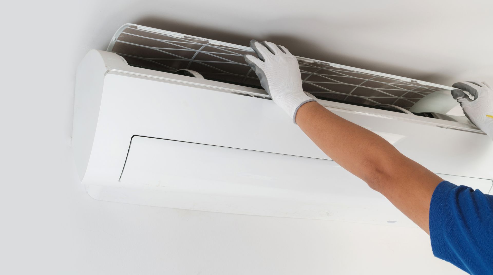 Technician repairing wall AC unit during heating system installation service inside home.
