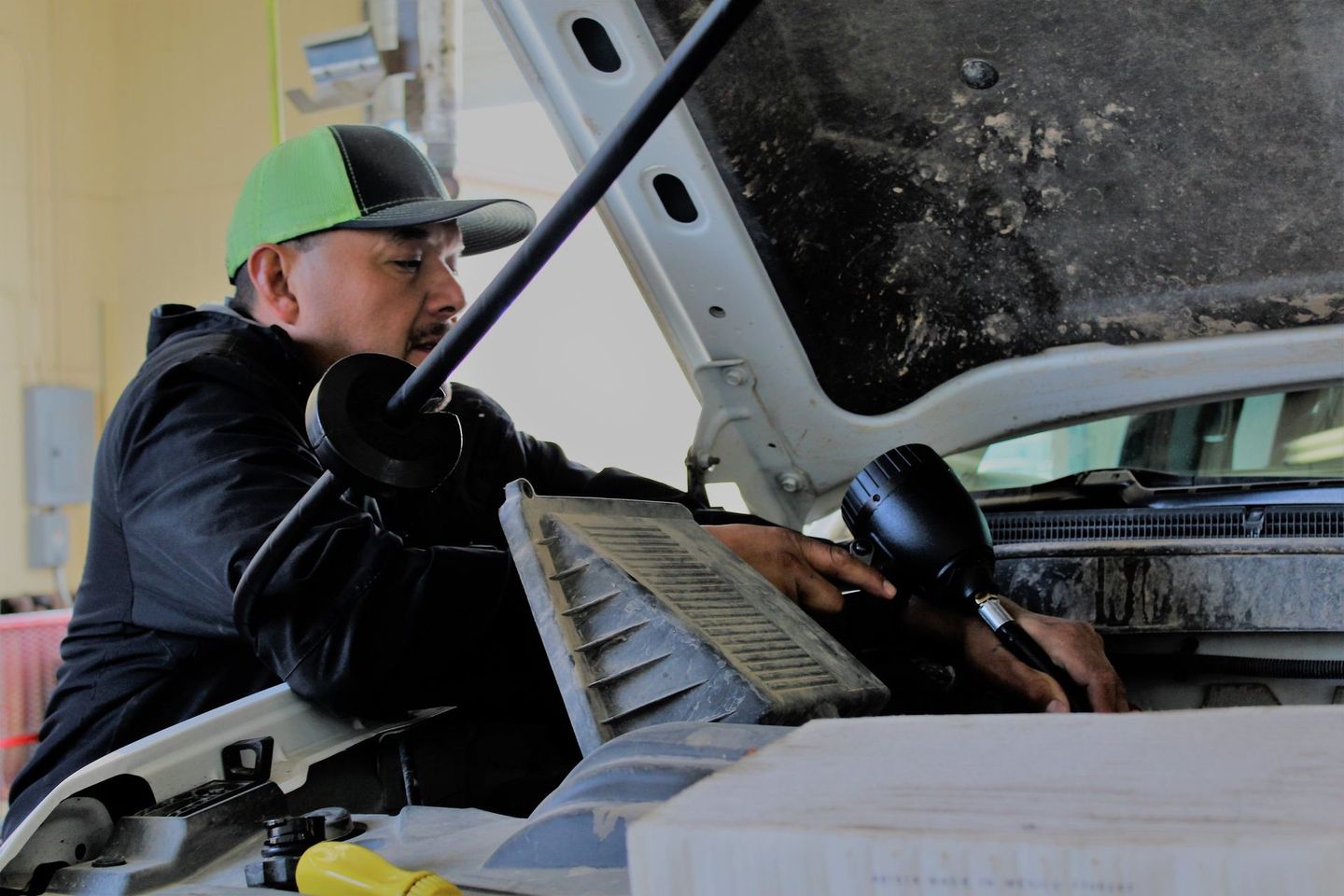 A man is working on a car with the hood open