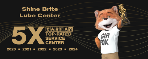 CARFAX fox mascot is holding a trophy in front of a sign that says shine brite lube center 5x top-rated service center