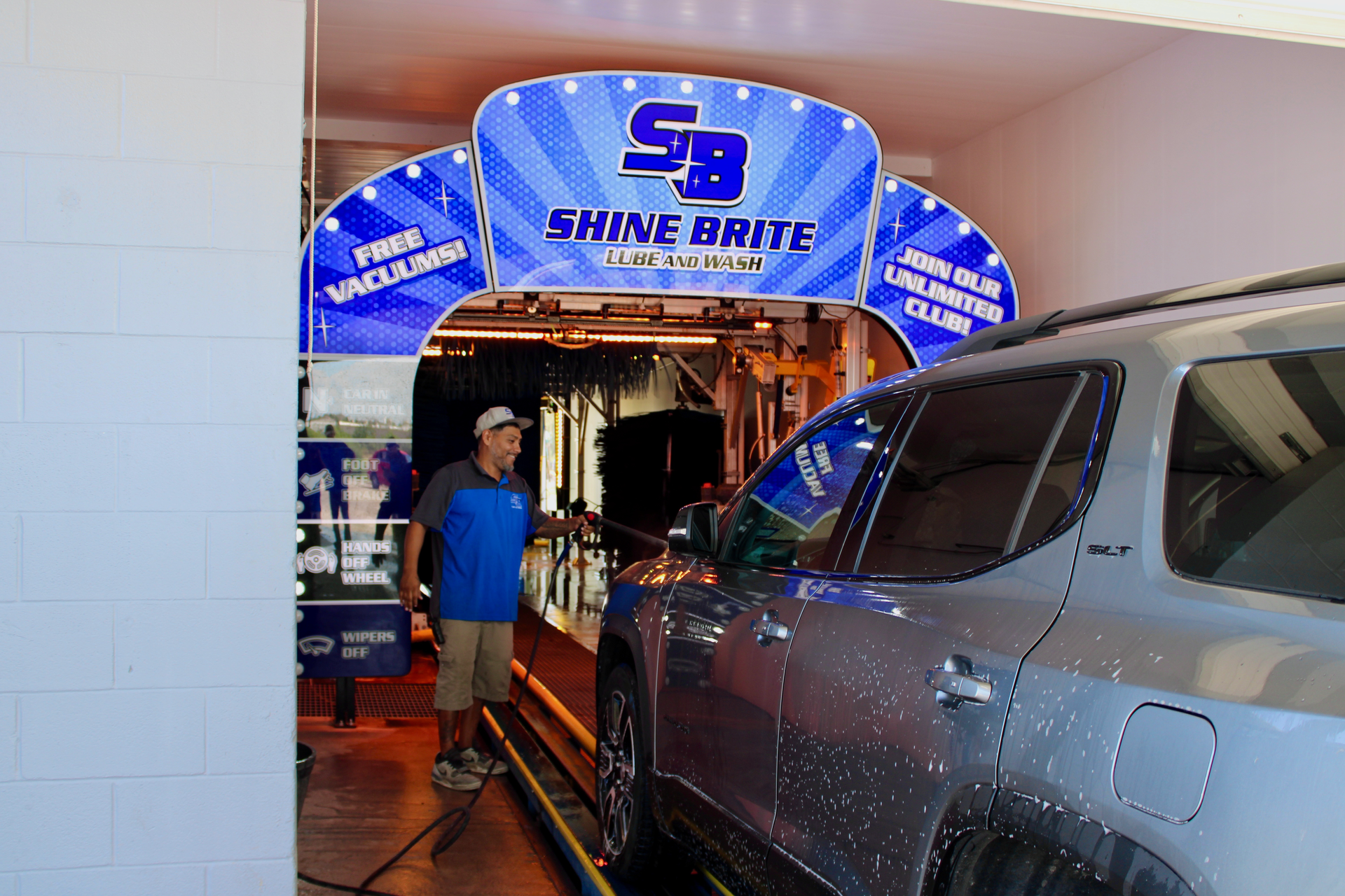 Man at car wash entrance with a silver SUV; 