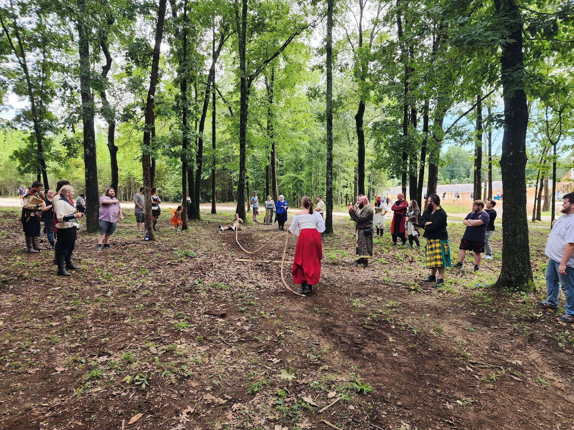 A group of people are sitting in the woods watching a performance.