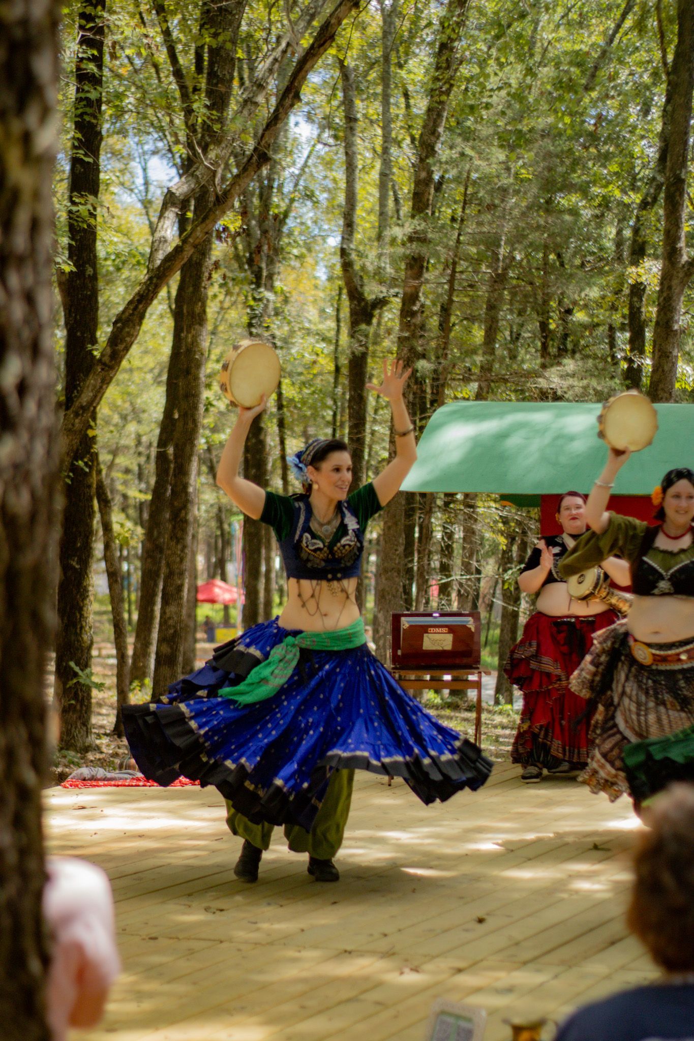 A group of belly dancers are dancing in the woods.