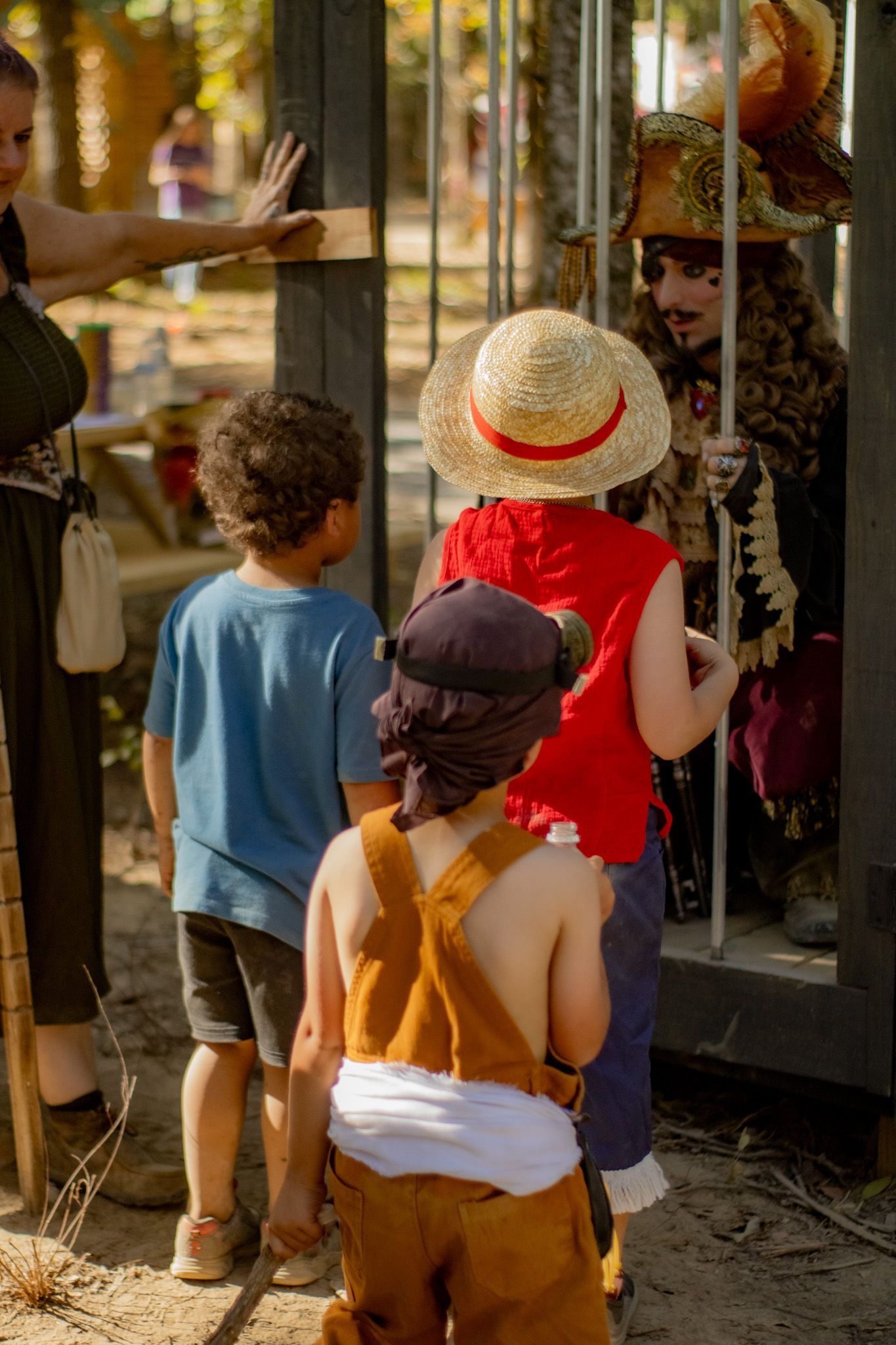 three kids dressed up talking to a man dressed up as a pirate.