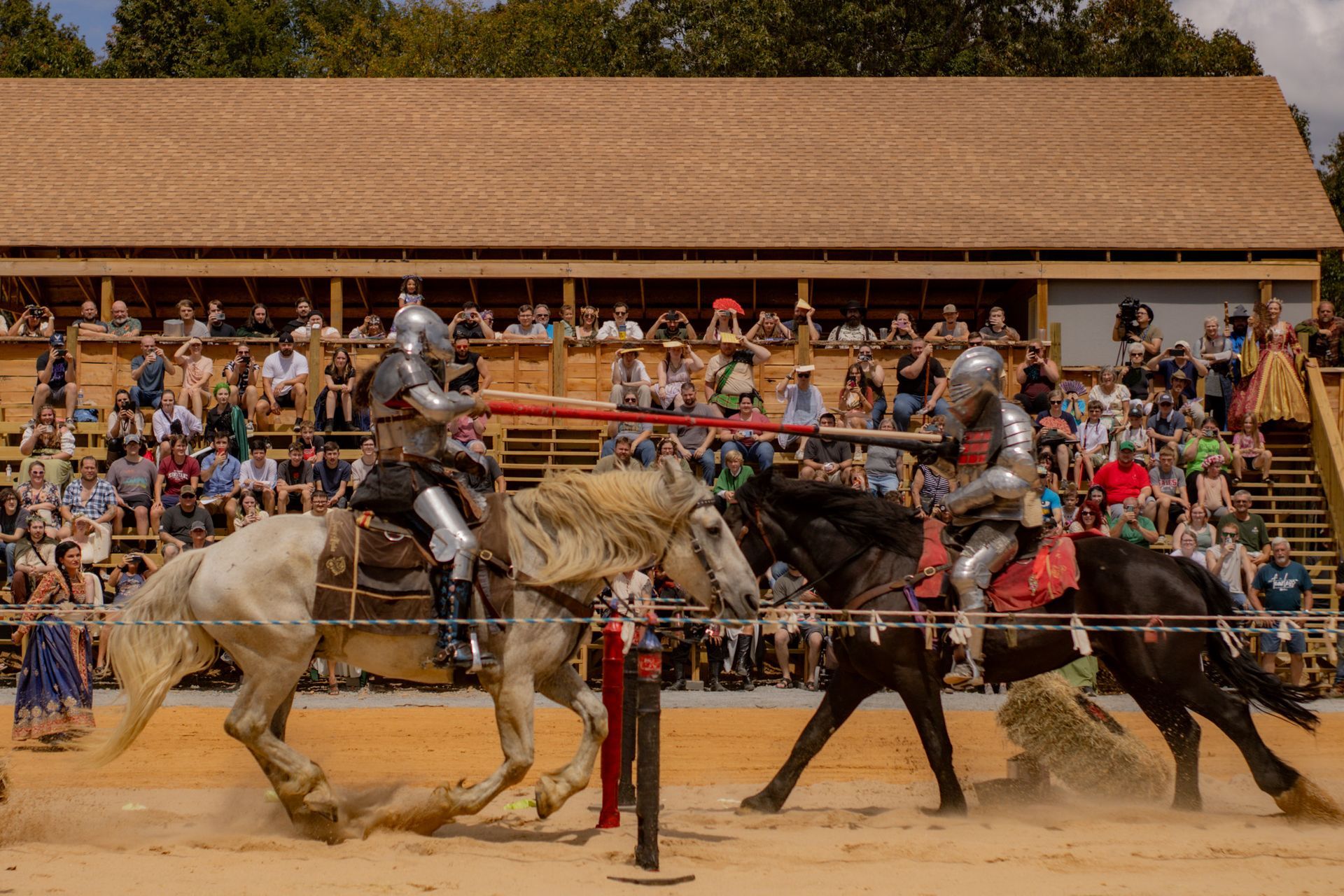 Two knights are fighting on horseback in front of a crowd.
