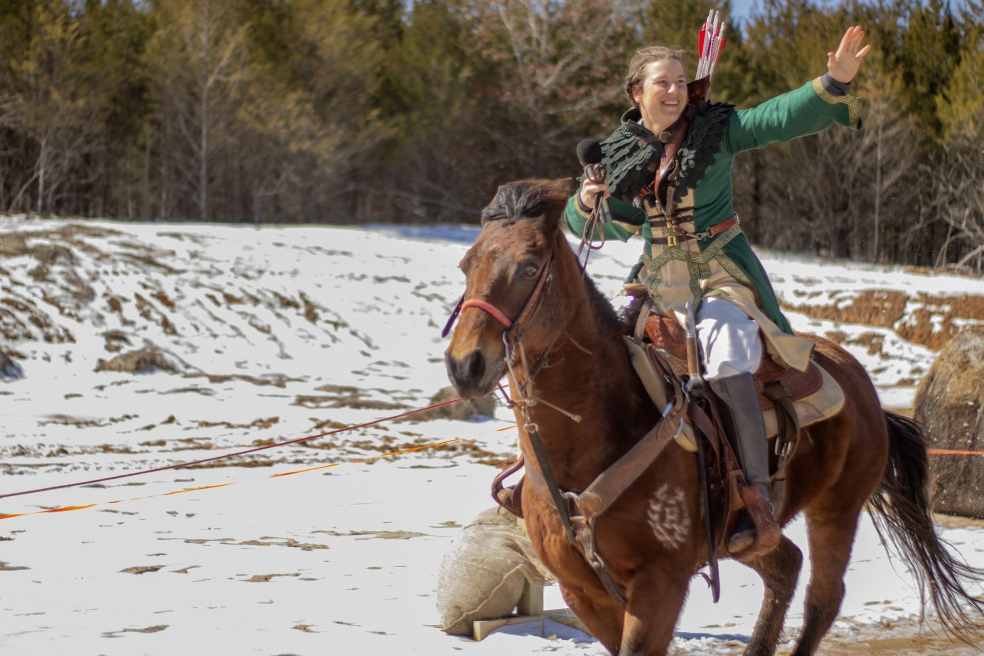 A woman in a green jacket is riding a horse in the snow.