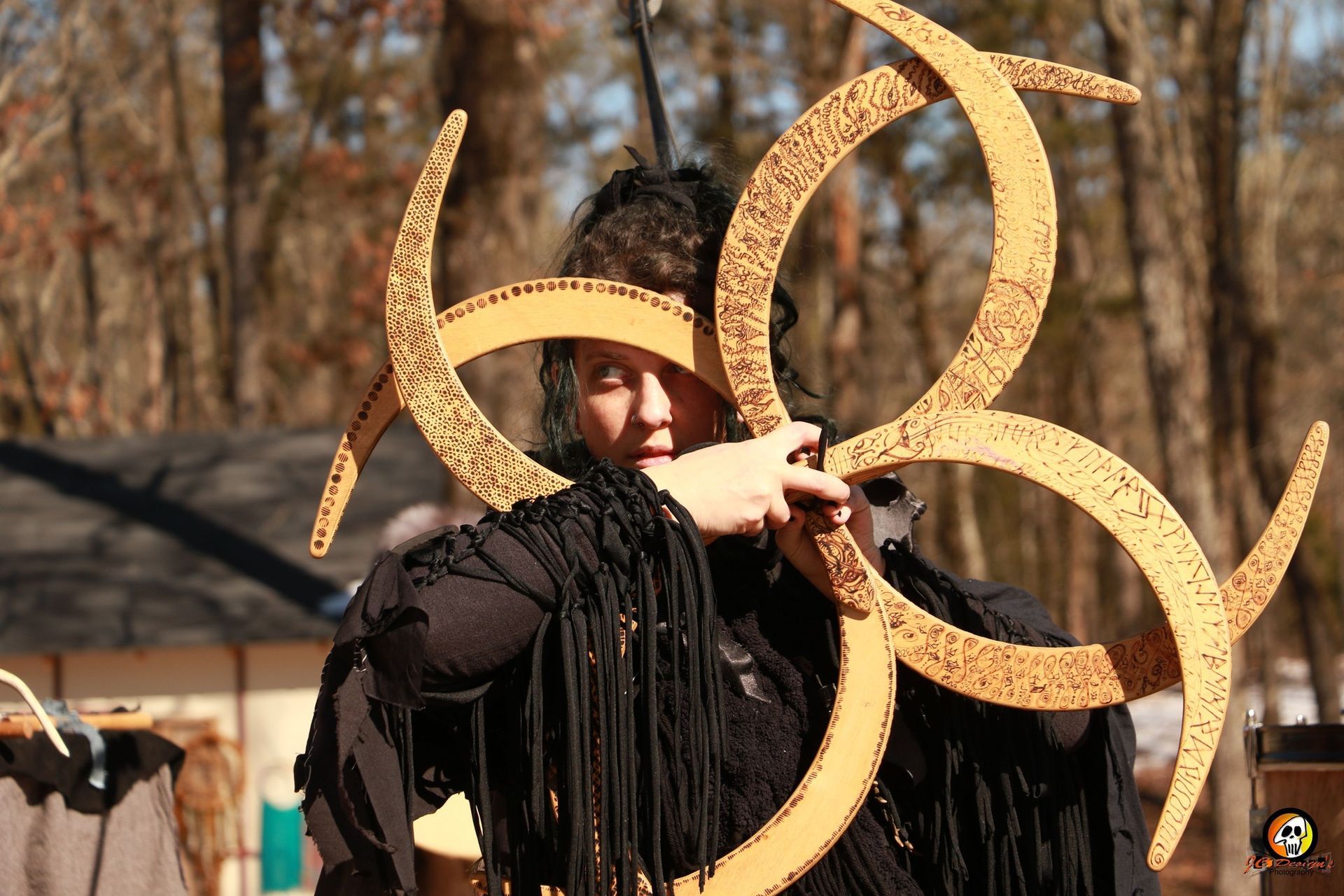 A woman in a black dress is holding a wooden object in her hand.