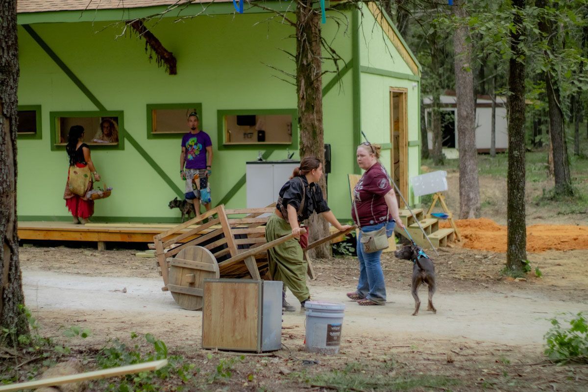 A group of people are standing in front of a green building.