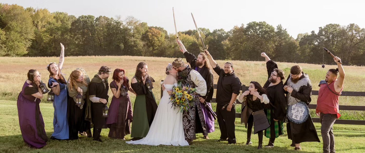 A bride and groom are posing for a picture with their wedding party on AR Renaissance Festival grounds.