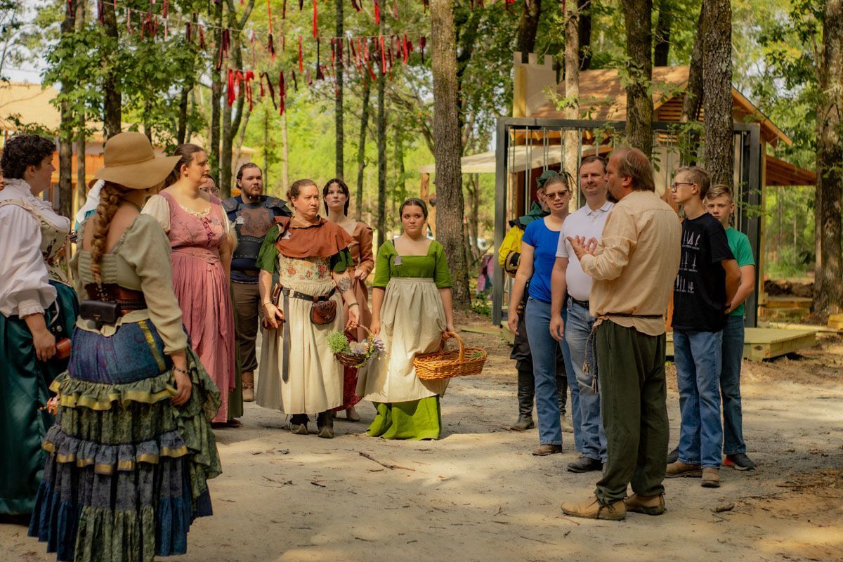 A group of women are dancing and playing tambourine in the woods