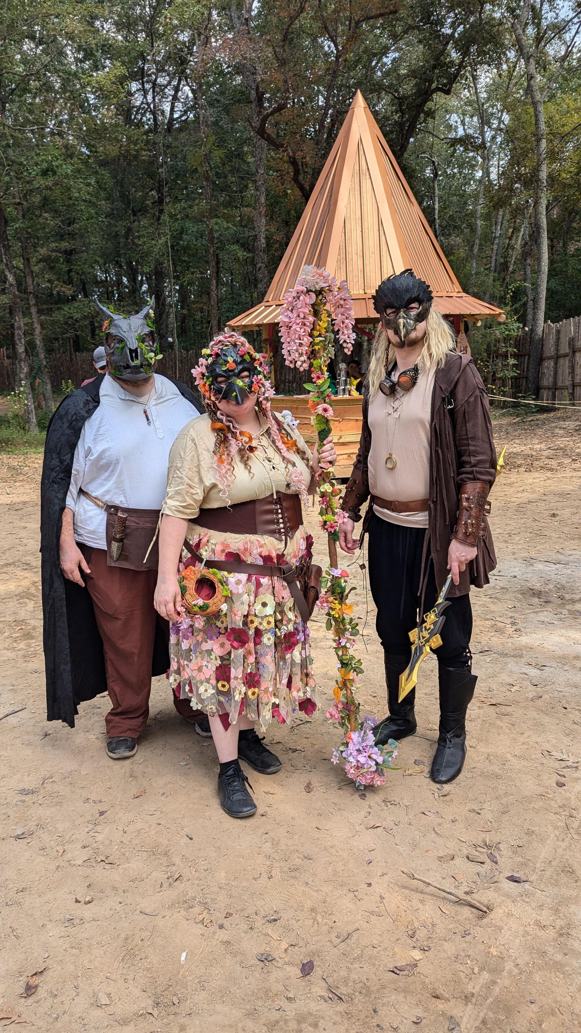 A group of people dressed in costumes are standing next to each other in a dirt field.