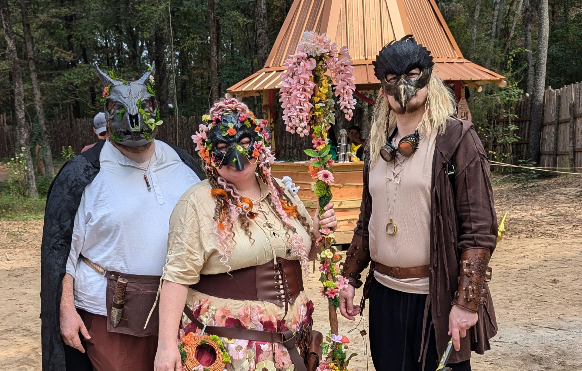 A group of people dressed in costumes are standing next to each other in a dirt field.