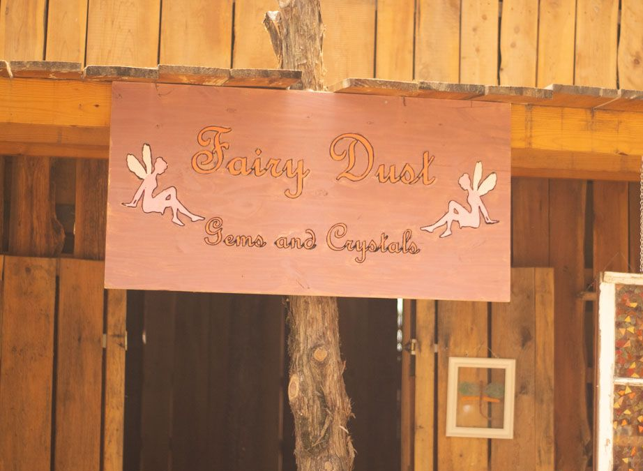 Sign for "Fairy Dust" shop, pink background, with fairies and text "Gems and Crystals"