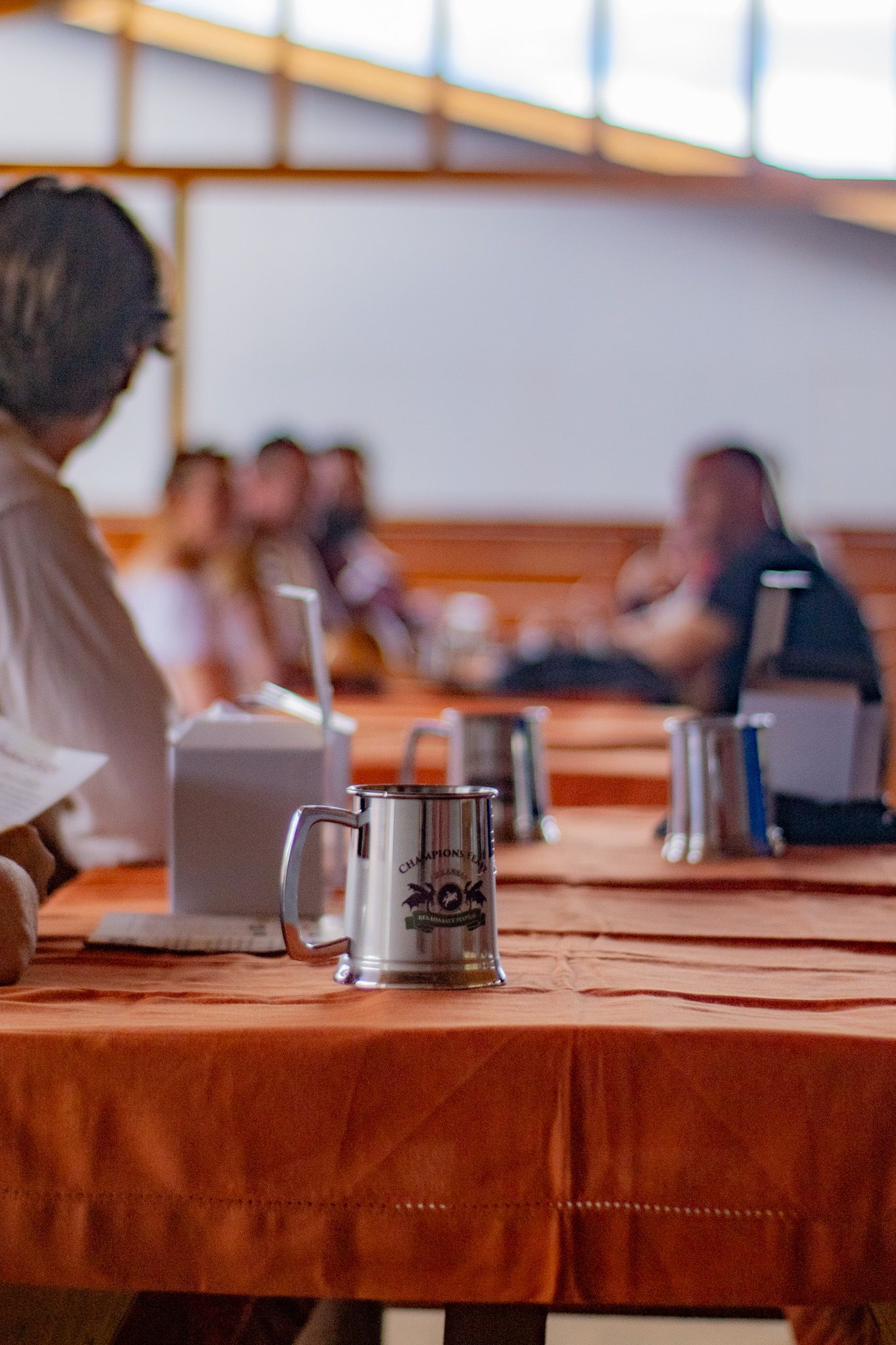 A group of people are sitting at tables with mugs on them.