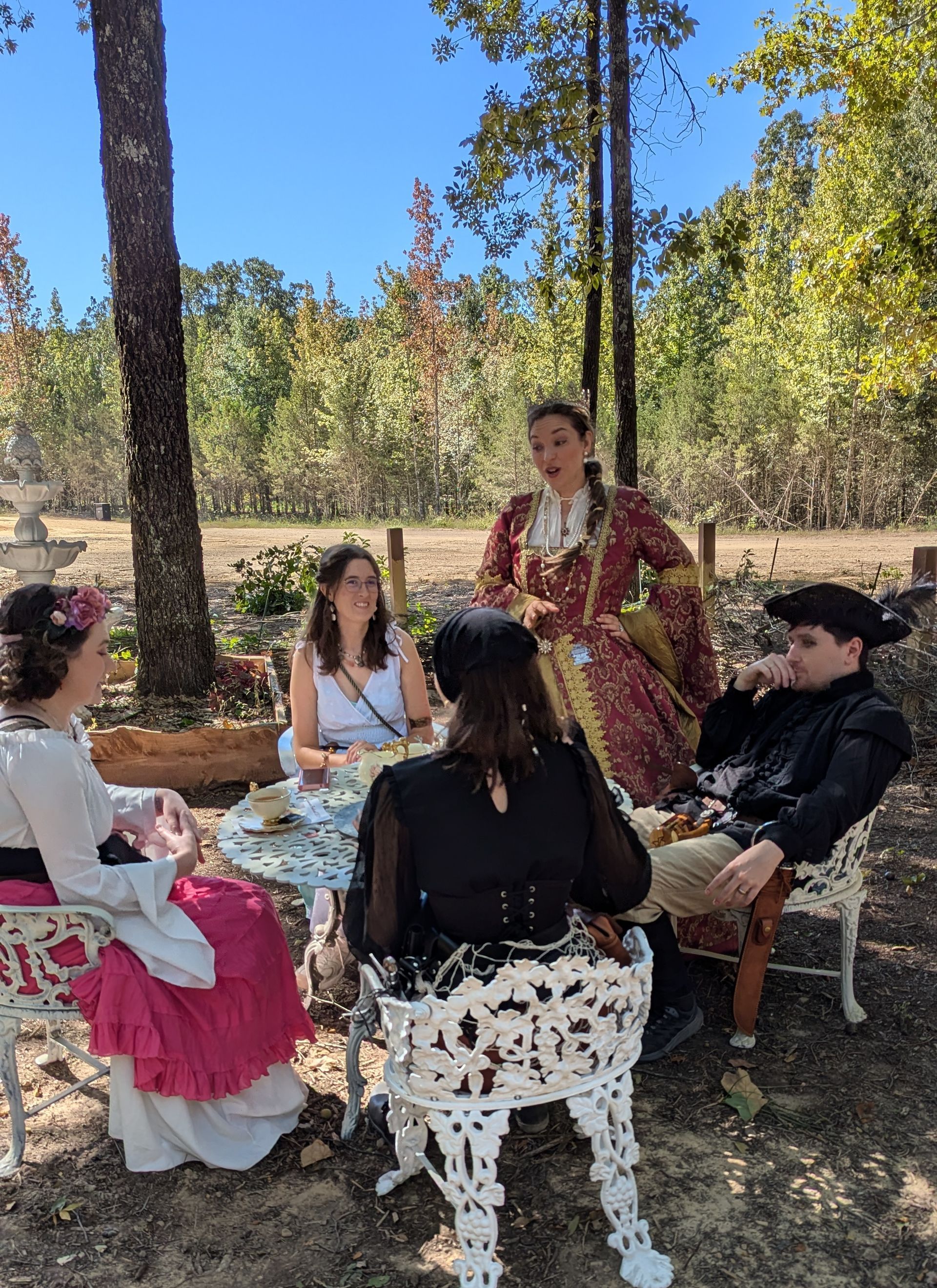 A group of people are sitting in the woods watching a performance.