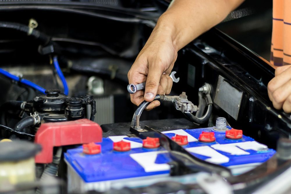 A Man is Fixing a Car Battery With a Wrench — Battery Assist QLD In Morayfield, QLD