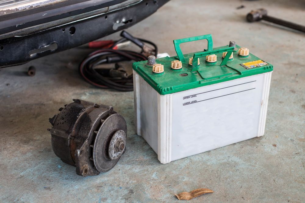 A Car Battery Is Sitting Next To A Broken Alternator — Battery Assist QLD In Kunda Park, QLD