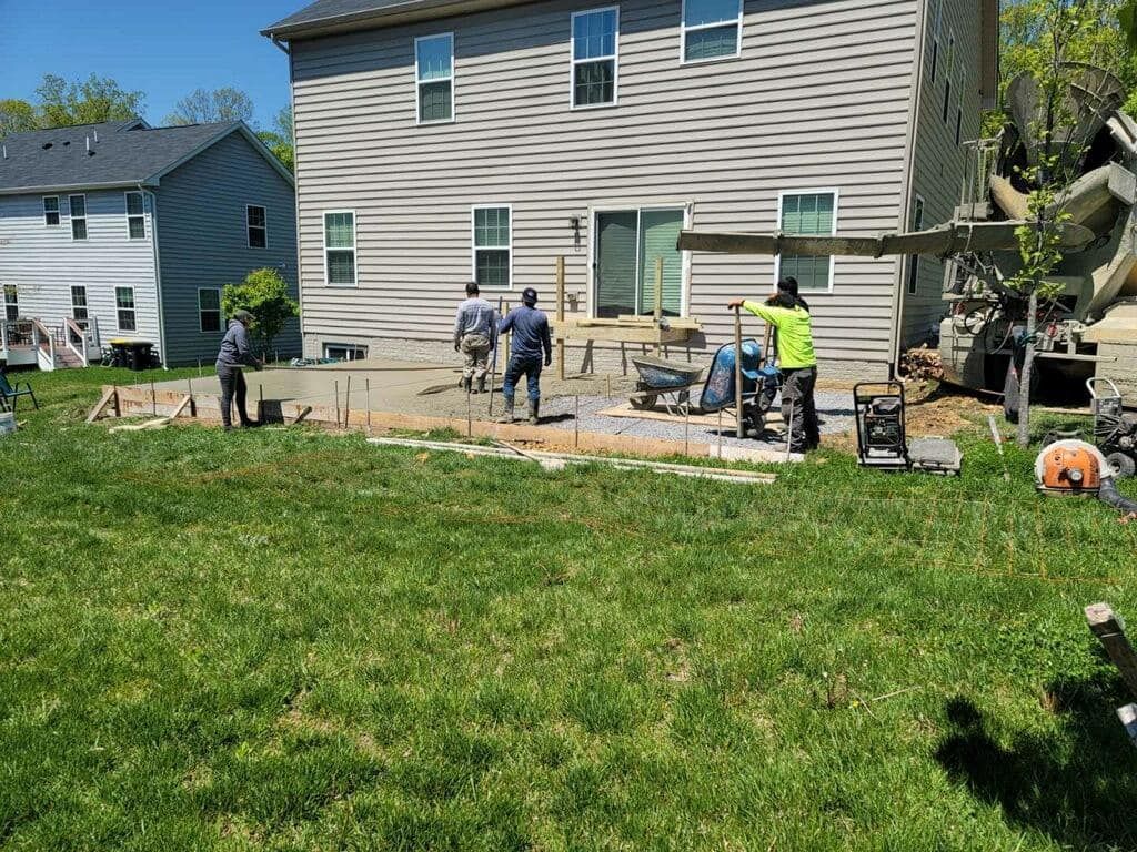 A group of people are working on a patio in front of a house.