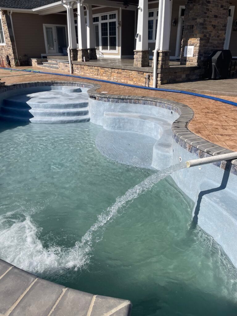 A large swimming pool with stairs and a house in the background.