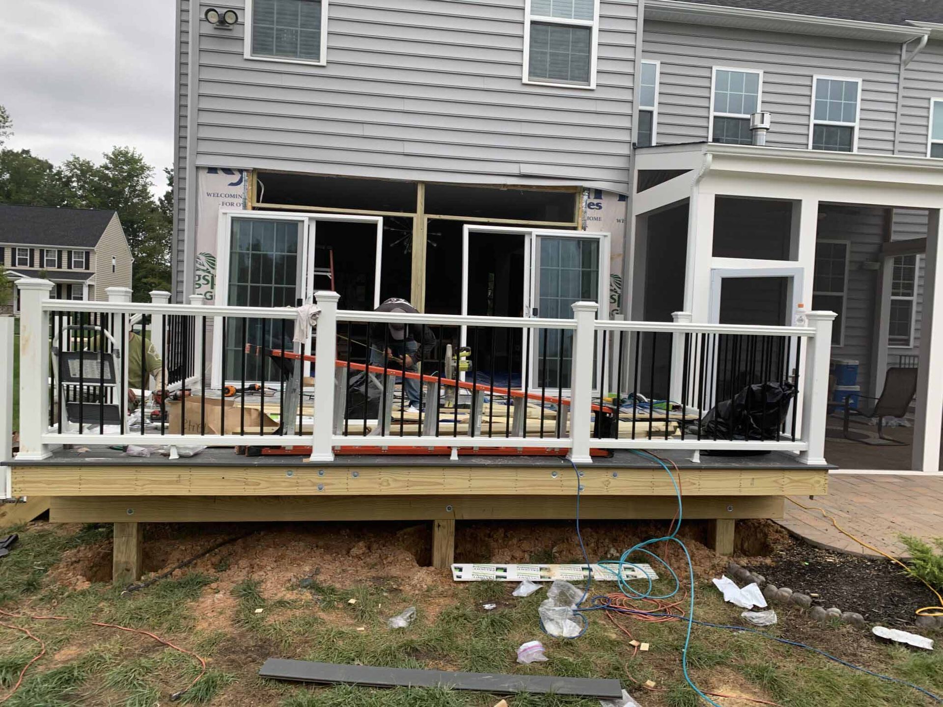 A deck is being built in front of a house with a screened in porch.