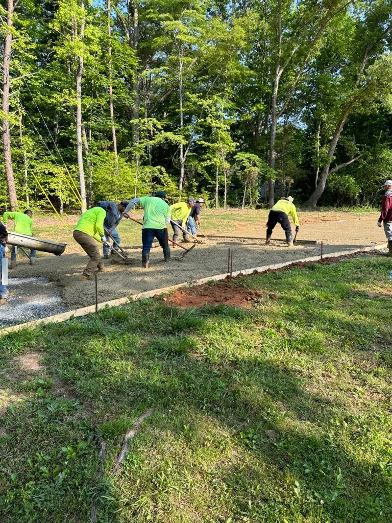 A group of people are working on a sidewalk in a park.