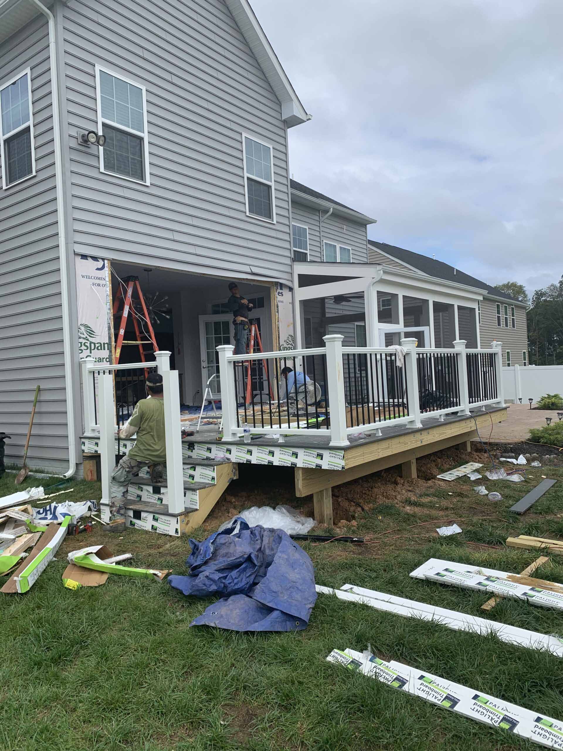 A man is working on a deck in front of a house.