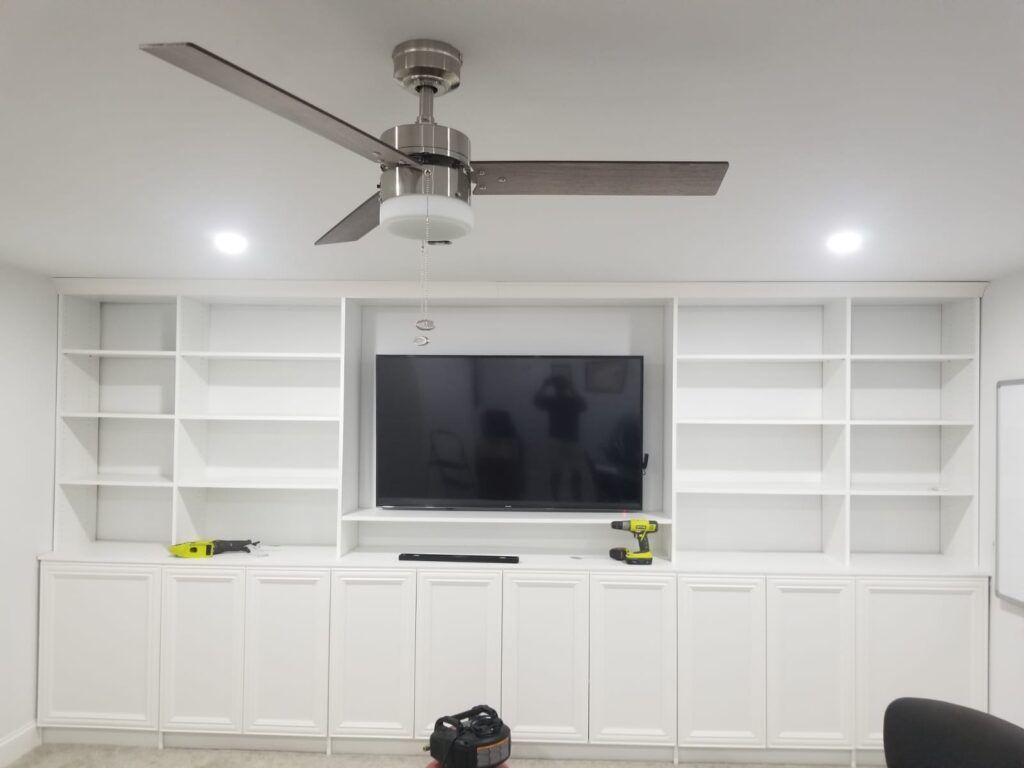 A living room with a ceiling fan and a flat screen tv.