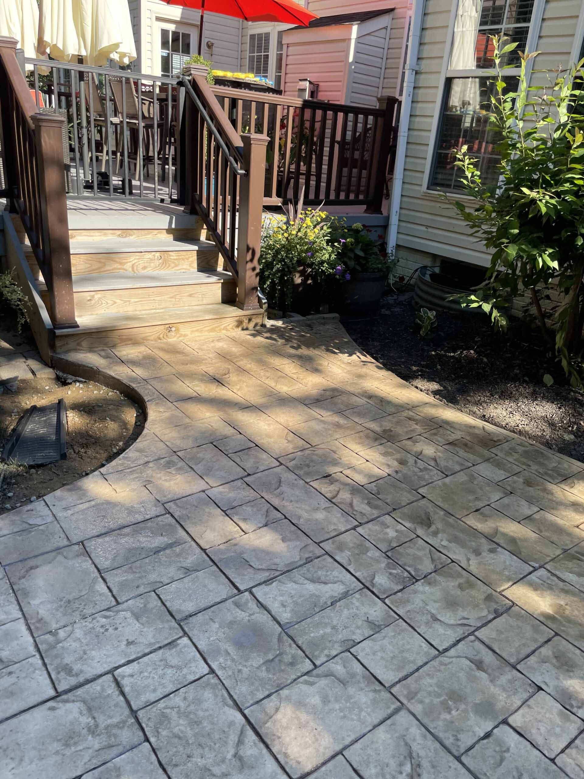 A patio with a deck and stairs leading to it.
