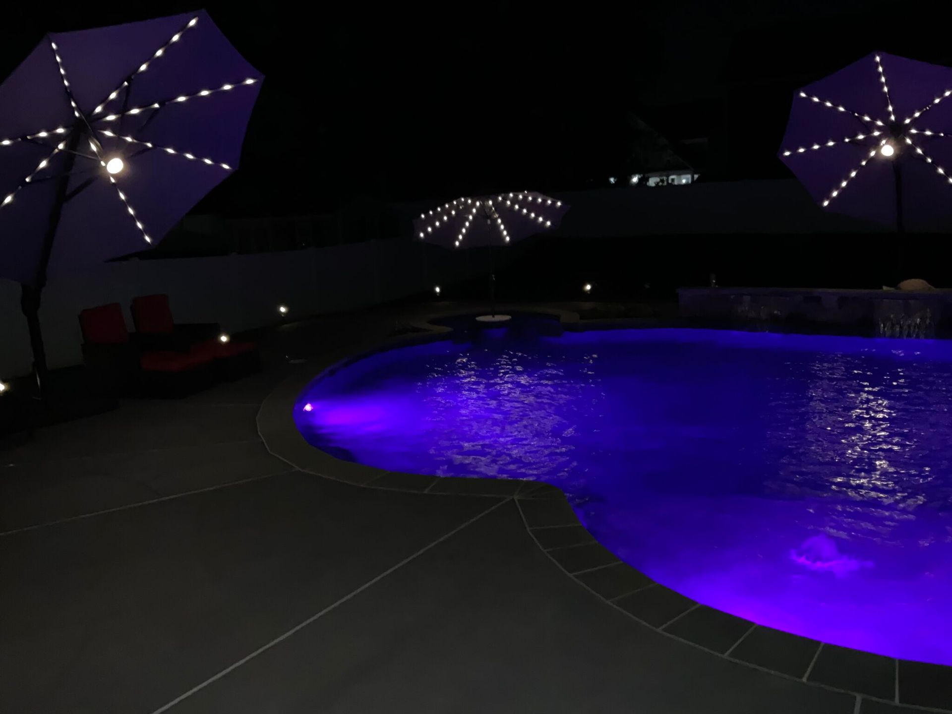 A swimming pool is lit up with purple lights at night
