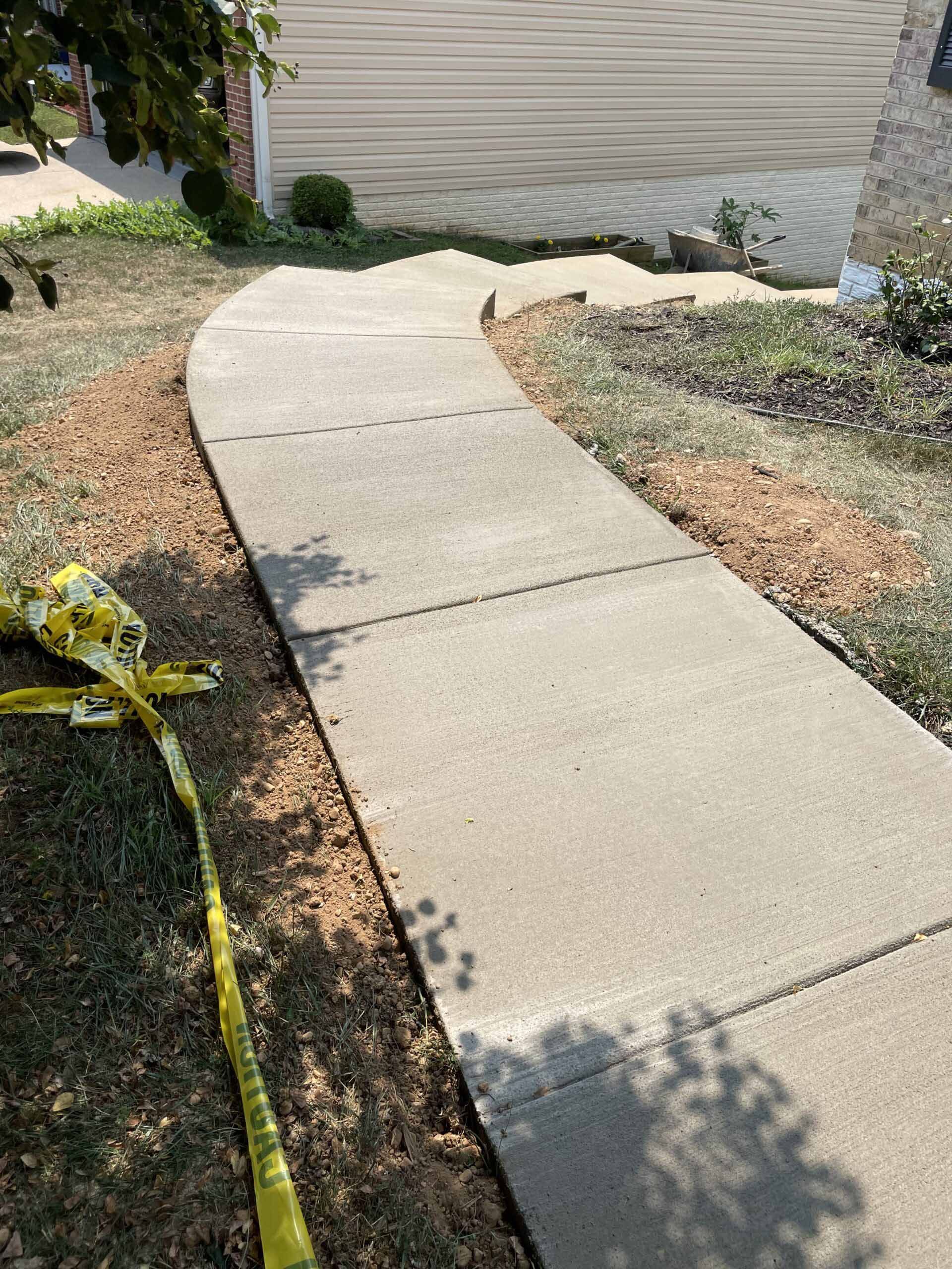 A concrete sidewalk with a yellow tape on the side of it.