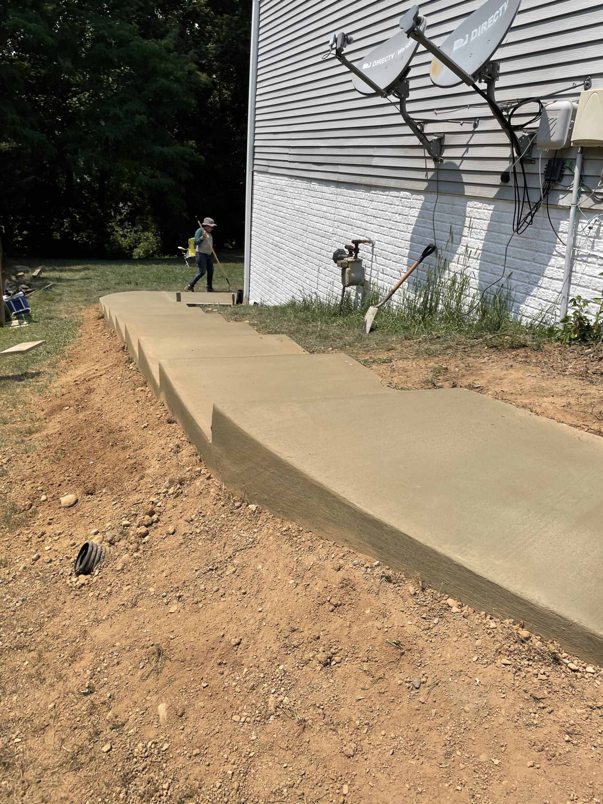 A concrete walkway is being built in front of a house.