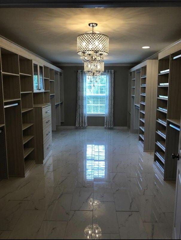 A large walk in closet with a chandelier hanging from the ceiling