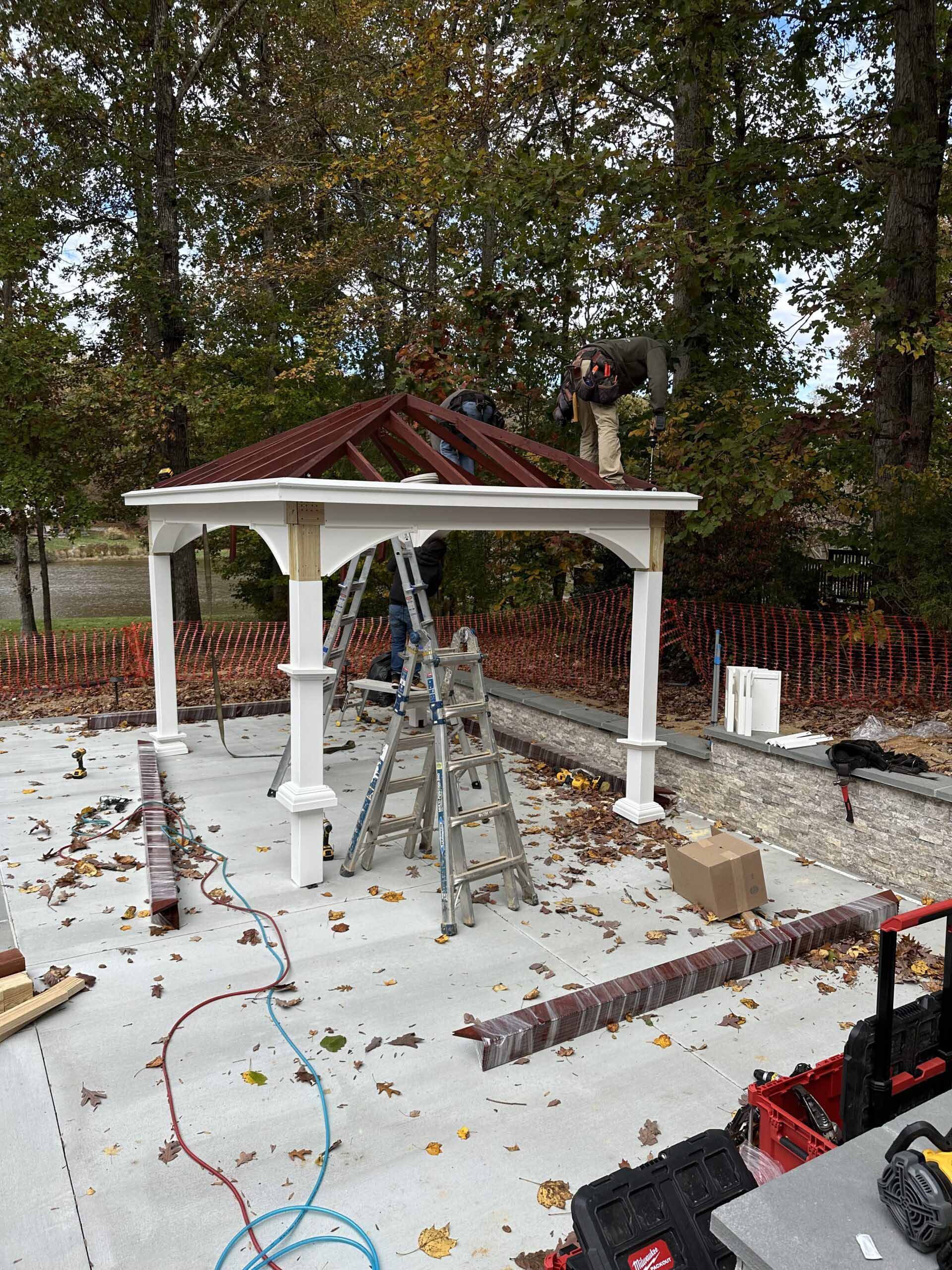 A man is working on the roof of a gazebo.