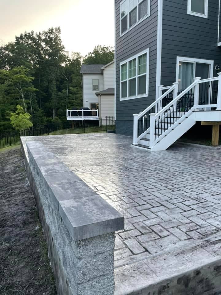 A patio with a deck and stairs in front of a house.