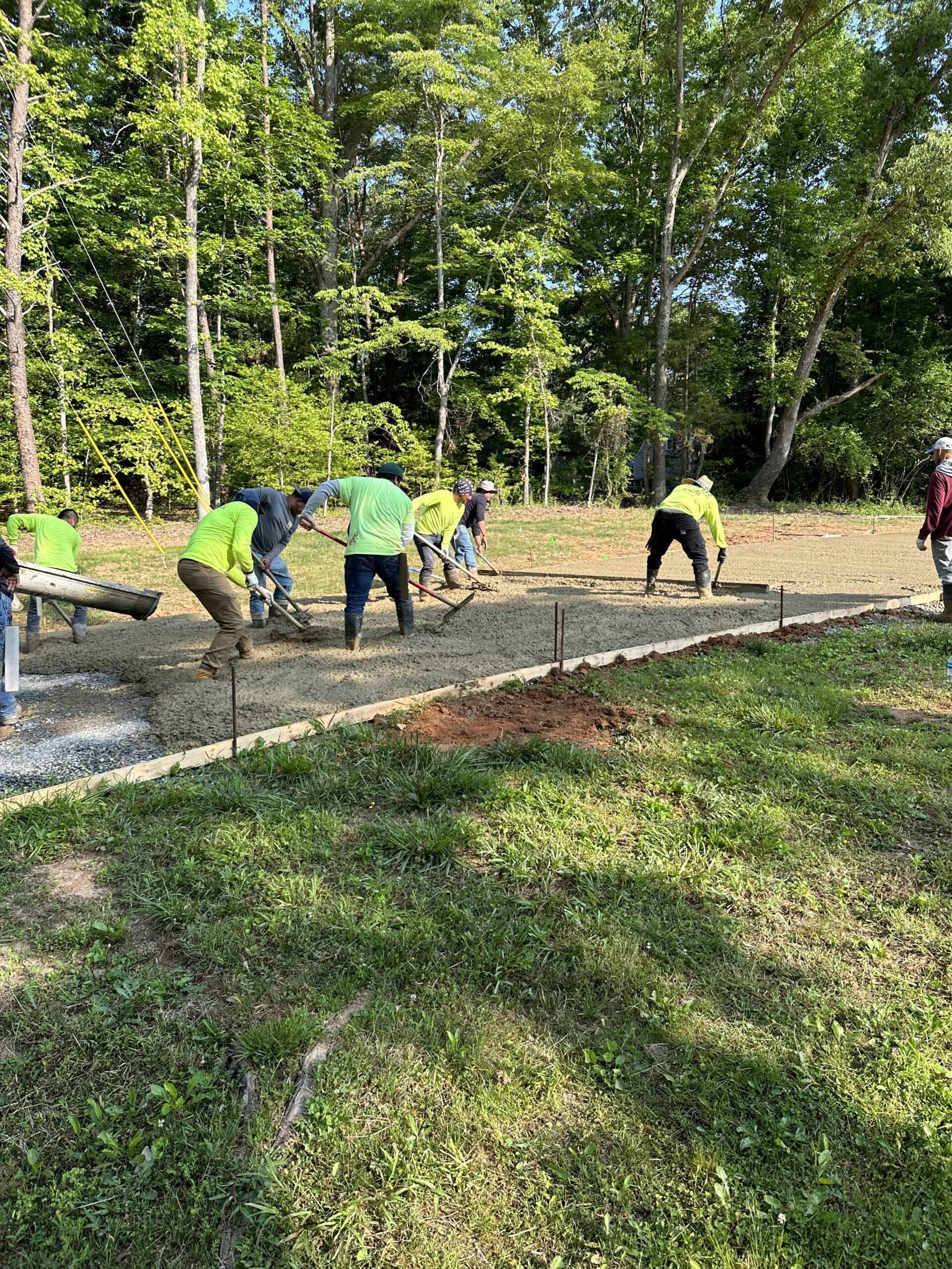 A group of people are working on a sidewalk in a field.