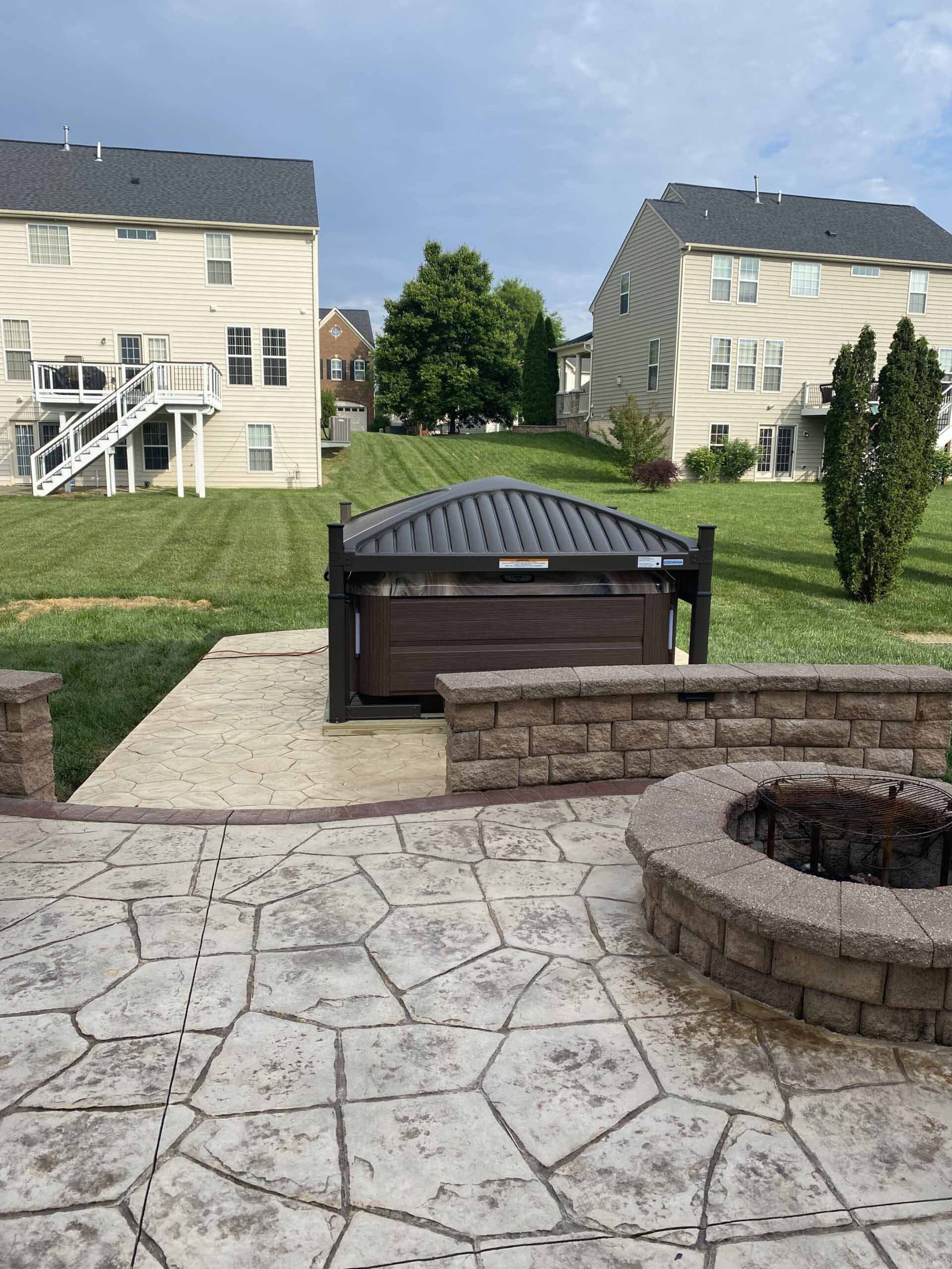 A hot tub is sitting on a patio next to a fire pit.