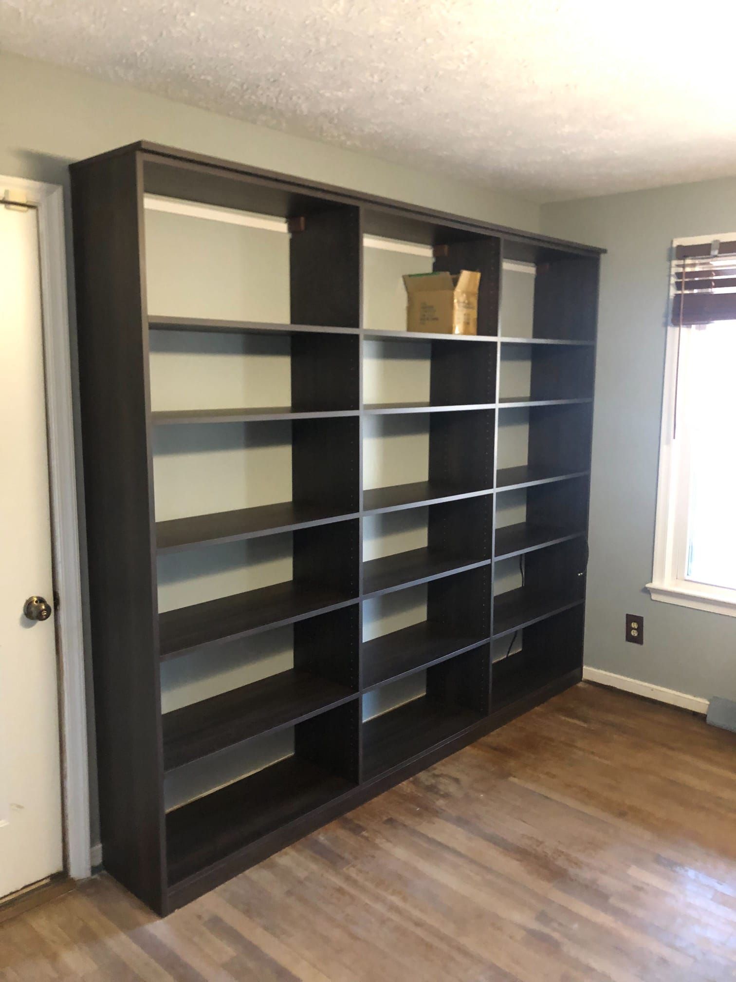 A room with a lot of shelves and a window.