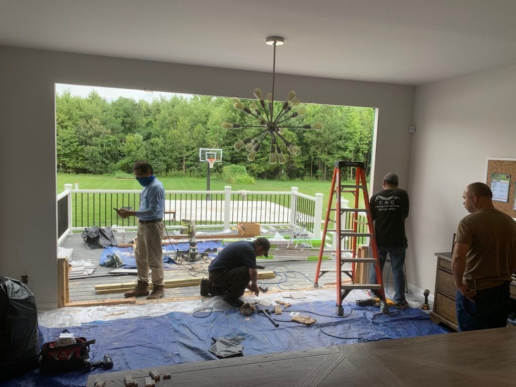 A group of men are working on a sliding glass door in a living room.